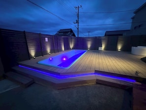 A wooden deck with a hot tub and blue LED lighting.