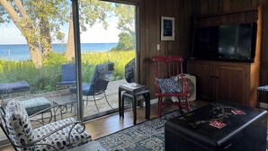 Ein Wohnzimmer mit einem großen Fernseher, einem roten Sessel und Meerblick durch eine Schiebetür.