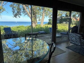 A glass table with a view of the ocean and patio furniture. - Lake Michigan Beach Time - Private Beach on Lake Michigan (Whitehall)