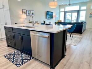 A modern kitchen with a large island, built-in appliances, and a dining area with a blue sofa.