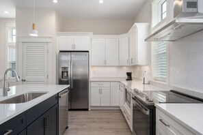 A modern kitchen with white cabinetry, stainless steel appliances, and a central island.