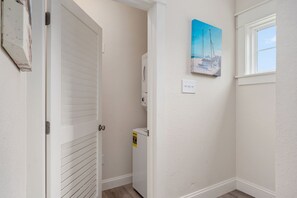A hallway with a white door, a wall-mounted heater, a power outlet, and a painting of boats.