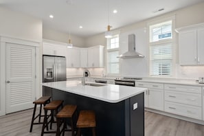 A modern kitchen with a large island, stainless steel appliances, and white cabinetry.