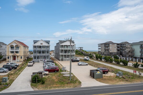 A coastal residential area with multiple apartment buildings, a parking lot, and a beach visible in the background.