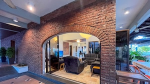 A modern interior with a brick wall archway leading to a living area with sofas and a coffee table. - Bangsar Private Pool Villa Kuala Lumpur (Kuala Lumpur)