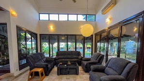 A spacious living room with a high ceiling, large windows, and a view of a garden. - Bangsar Private Pool Villa Kuala Lumpur (Kuala Lumpur)