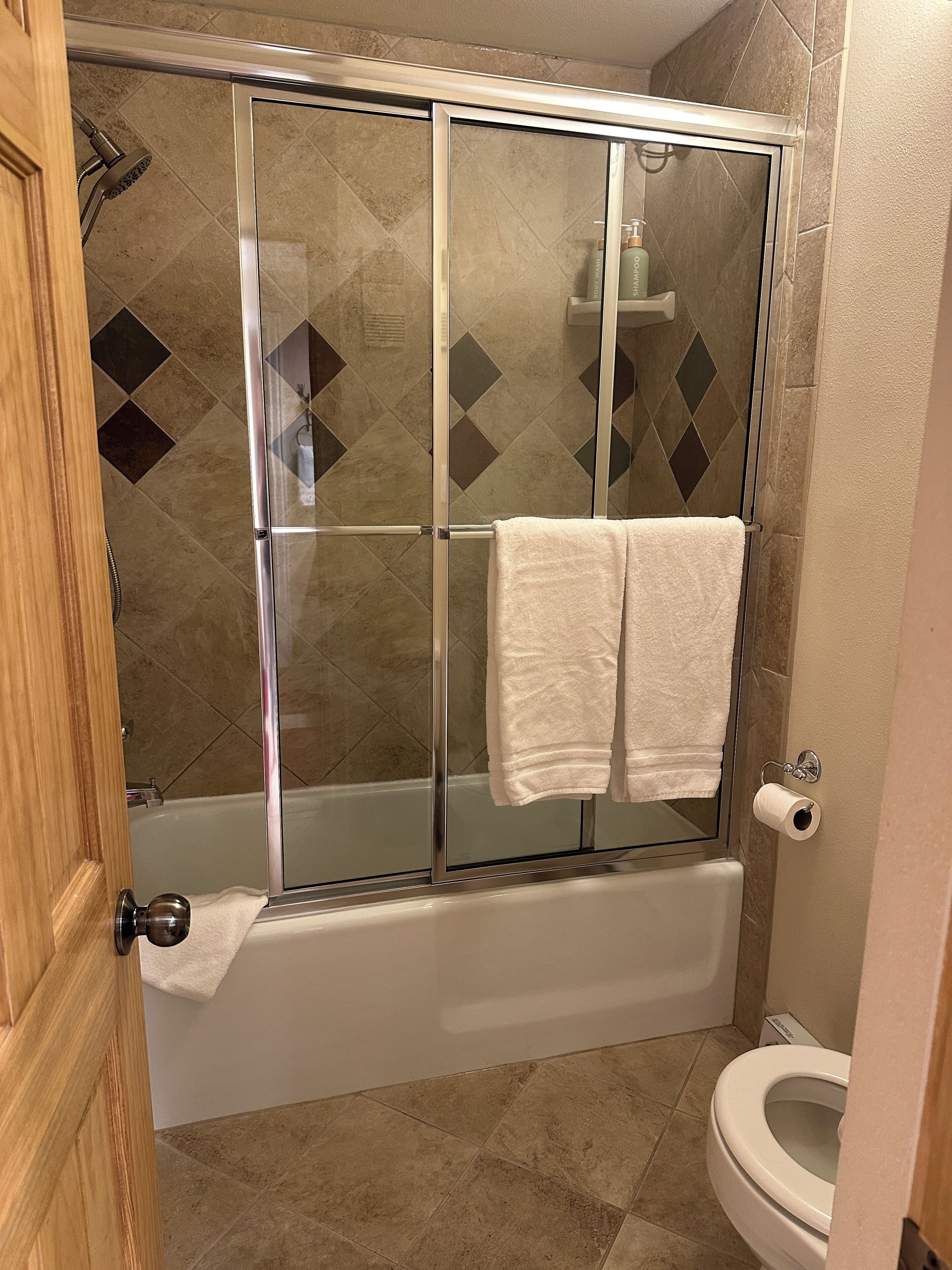 A bathroom with a glass-enclosed shower, a bathtub, and a toilet.