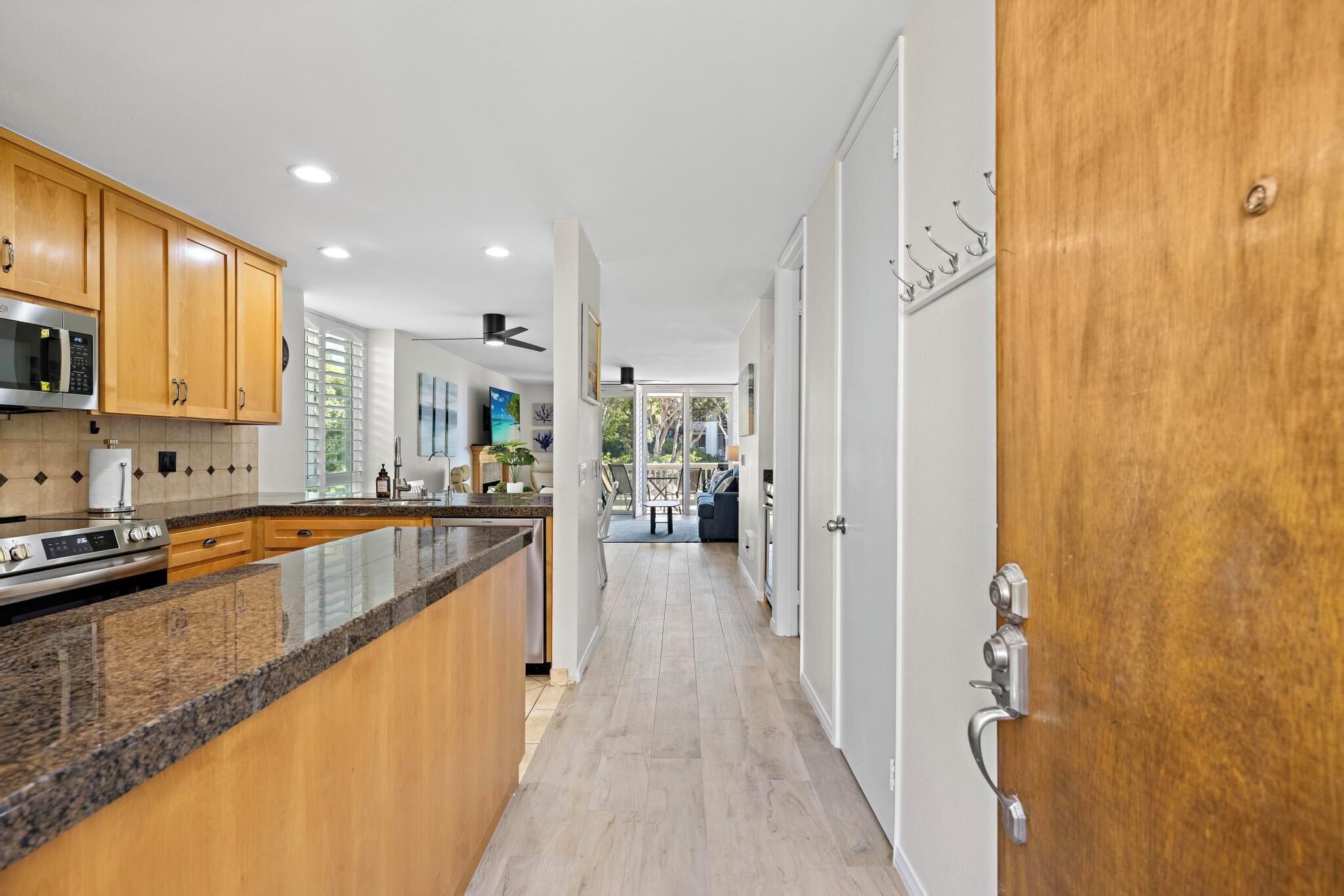 A modern kitchen with wooden cabinets, a granite countertop, and stainless steel appliances.