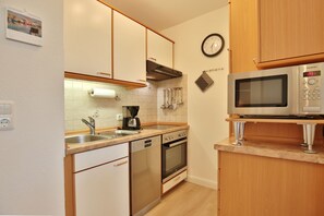 A compact kitchen with a dishwasher, oven, coffee maker, and a microwave.