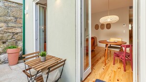 A small, cozy room with a wooden table and chairs, a potted plant, and a sliding glass door leading to another room. - D&S -JB Apartments - A (Oporto)