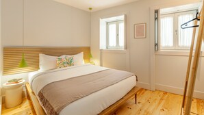 A bedroom with a wooden bed, a bedside table, a hanging lamp, and a window with a view. - D&S -JB Apartments - A (Oporto)