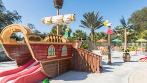 A pirate-themed play area with a ship structure, slides, and outdoor seating.