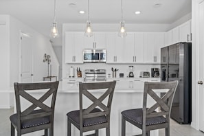 A modern kitchen with white cabinets, stainless steel appliances, and pendant lighting. - 3 BR 2 5 BA Villa Sleeps 8 Eve102 (Davenport)