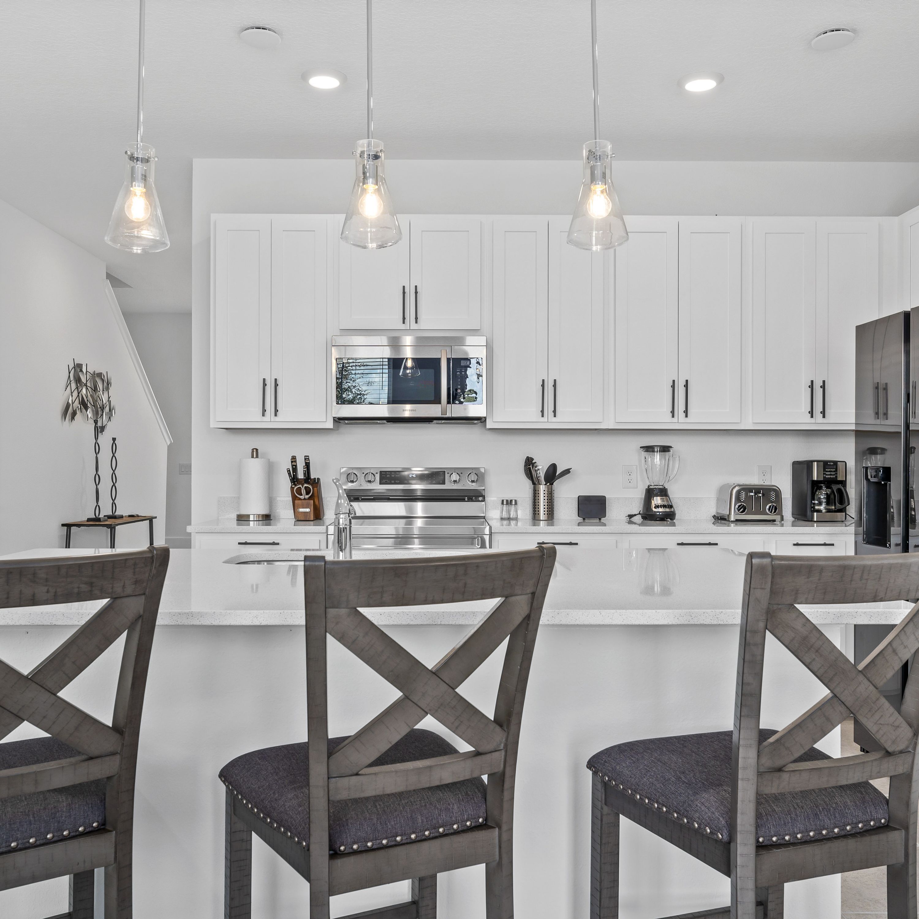 A modern kitchen with white cabinets, stainless steel appliances, and a central island with bar stools.