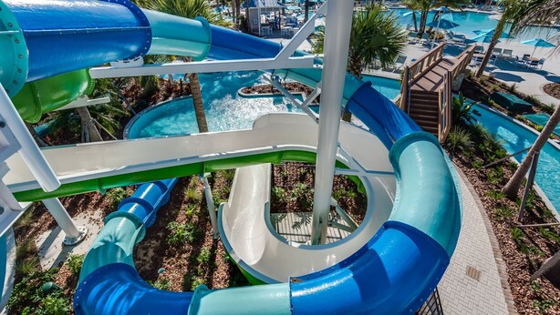 A water park with multiple slides and pools, surrounded by palm trees and lounge areas. - Amazing Modern Home Pool Spa Game Room Wi101 (Davenport)