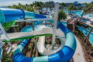 A water park with multiple slides and pools, surrounded by palm trees and lounge areas. - Amazing Modern Home Pool Spa Game Room Wi101 (Davenport)