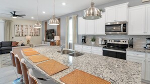 A modern kitchen with granite countertops, stainless steel appliances, and a central island with bar stools. - Amazing Modern Home Pool Spa Game Room Wi101 (Davenport)