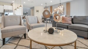A modern living room with a round marble coffee table, two armchairs, a sofa, and a dining area in the background. - Amazing Modern Home Pool Spa Game Room Wi101 (Davenport)