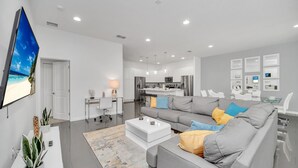 Una sala de estar moderna con un sofá gris, una mesa de centro y un televisor montado en la pared.