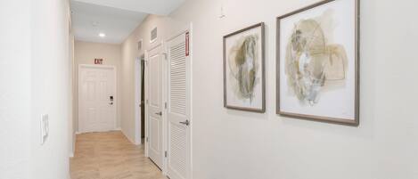A hallway with a bench, two framed abstract paintings, and a door marked "EXIT".