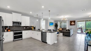 A modern kitchen with white cabinets, stainless steel appliances, and a central island.