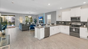 A modern kitchen with white cabinets, stainless steel appliances, and a large island.