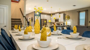 A dining table set with white plates, yellow napkins, and yellow flowers in vases. - Disney Decorated Home 8min to Disneyworld Pool Spa Sleeps 22 Stl104 (Kissimmee)