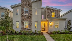 A modern two-story house with a stone facade, multiple windows, and a well-maintained lawn. - Disney Decorated Home 8min to Disneyworld Pool Spa Sleeps 22 Stl104 (Kissimmee)