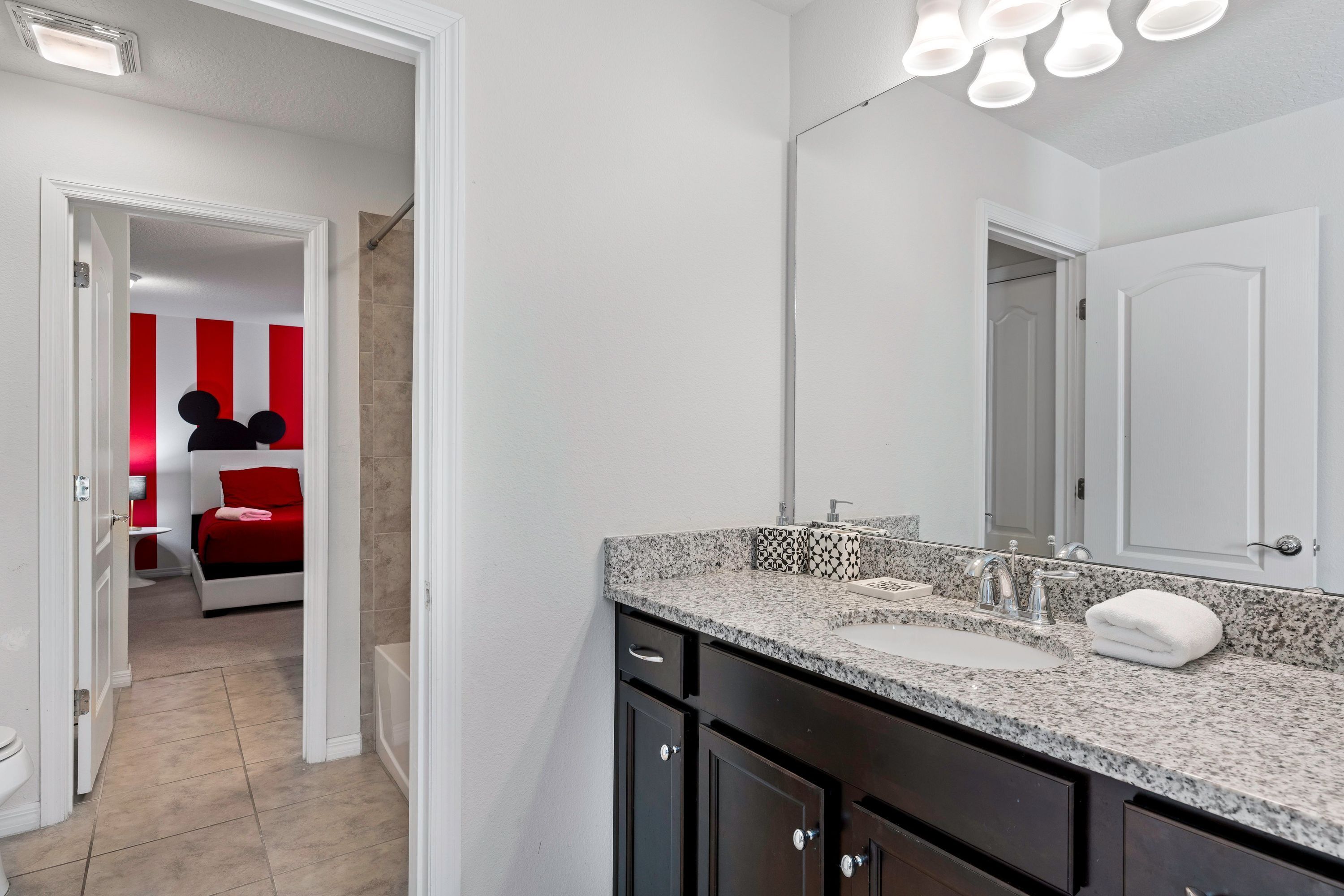 A bathroom with a granite countertop, a sink, and a mirror.