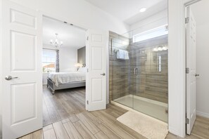 A modern bathroom with a glass shower enclosure, a white door, and a wooden floor. - Fun in Every Corner 14 BR Home Sol104 (Davenport)