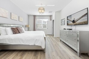 Ein Schlafzimmer mit Bett, Schminktisch, einer Deckenleuchte und Kunstwerken an den Wänden.