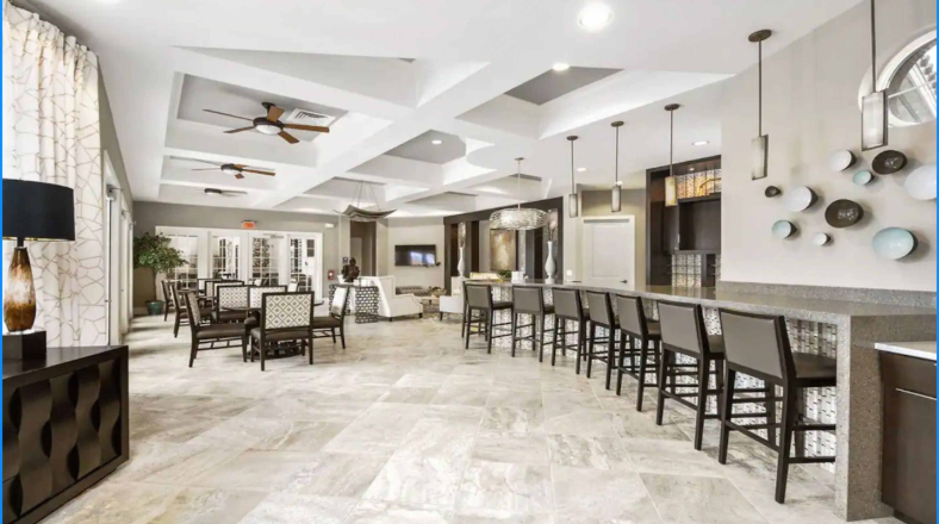 A spacious kitchen with a long island, modern pendant lighting, and a ceiling fan.
