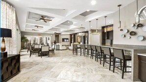 Una cocina amplia con una isla central alargada, iluminación colgante moderna y un ventilador de techo.