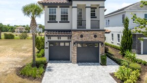 A two-story house with a garage, a stone facade, and a tiled roof. - Entire Home in Four Corners Florida Reu101 (Kissimmee)
