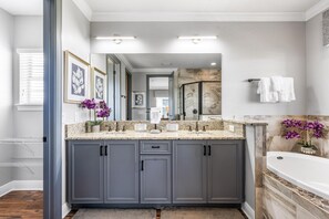 Un bagno moderno con mobili grigi, un piano di lavoro in marmo e una vasca da bagno.