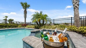 A poolside area with a drink bucket containing bottles and a glass. - Entire Home in Four Corners Florida Reu101 (Kissimmee)