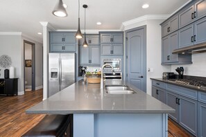 A modern kitchen with a large island, stainless steel appliances, and blue cabinetry. - Entire Home in Four Corners Florida Reu101 (Kissimmee)