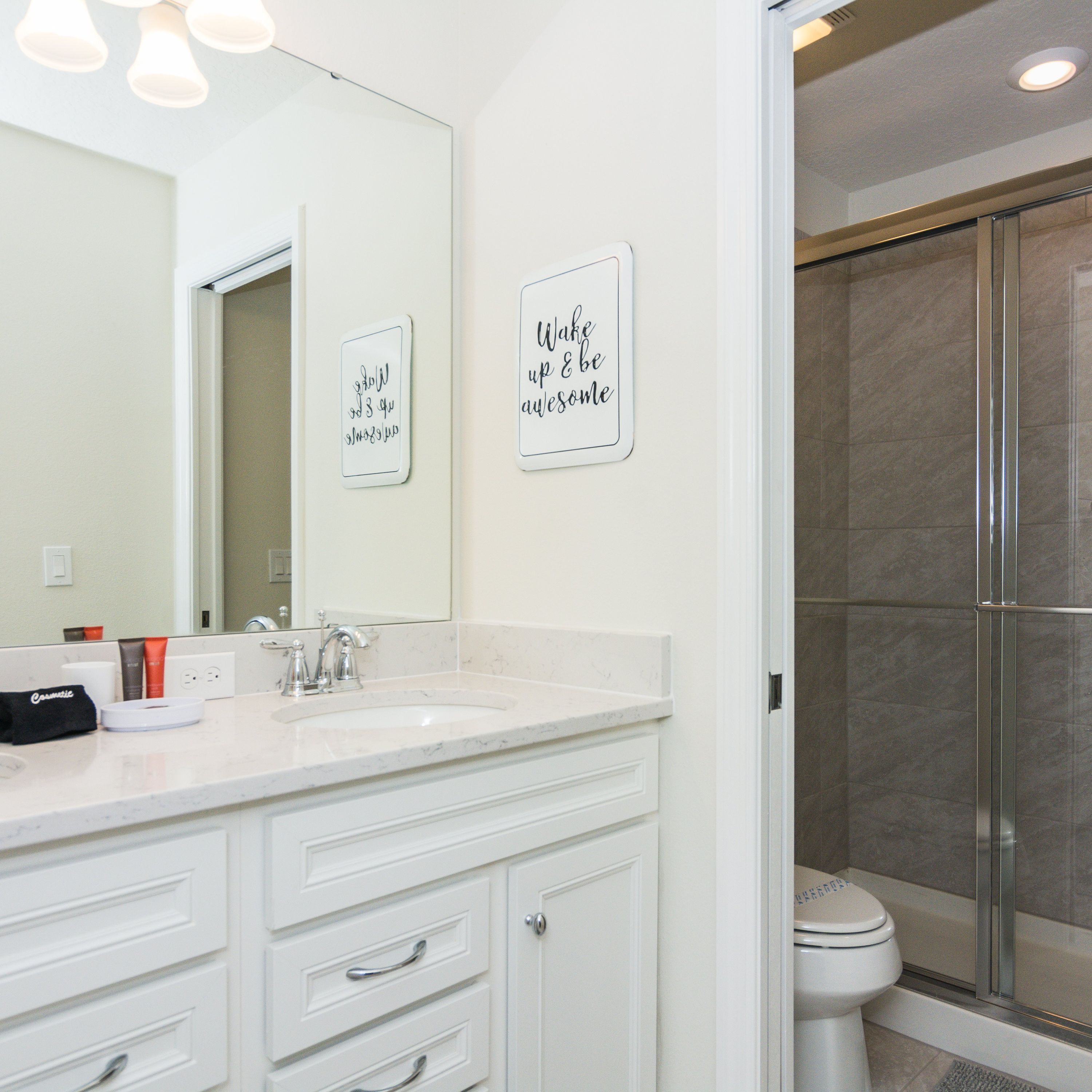 Un bagno moderno con un mobile lavabo bianco, uno specchio grande e due cartelli motivazionali.