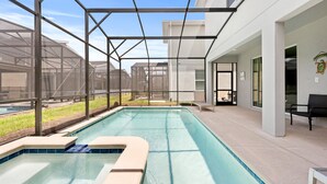 A swimming pool with a glass enclosure, surrounded by a patio area with outdoor furniture. - Dashing Family Home Stl113 (Kissimmee)