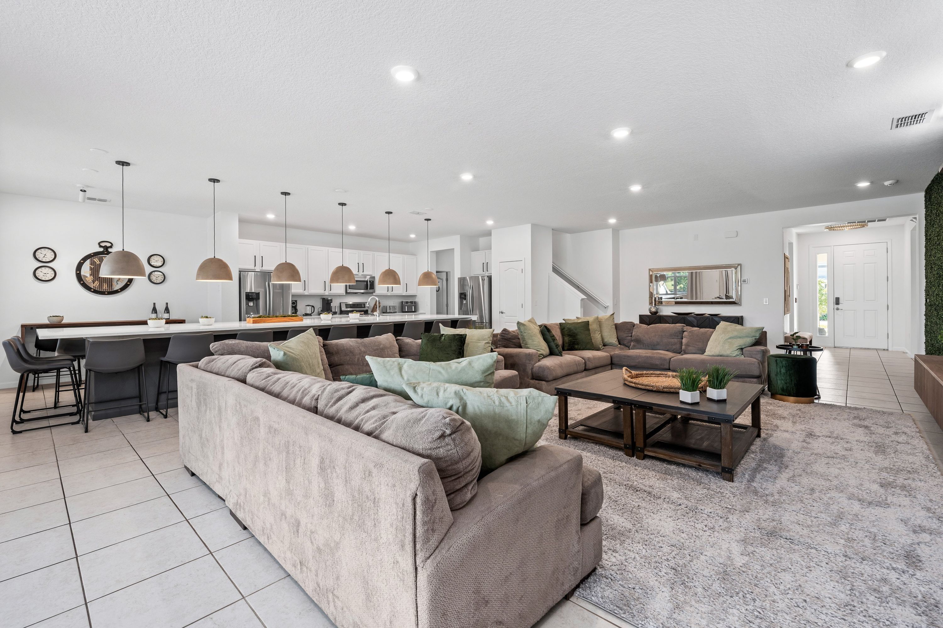 A modern living room with a large sectional sofa, a coffee table, and a dining area with bar stools.