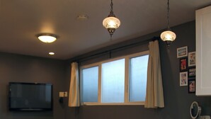 Une cuisine moderne avec des meubles blancs, un canapé jaune et des luminaires suspendus.