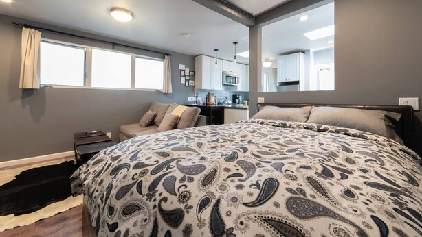 Une chambre moderne avec un grand lit, un canapé et un coin cuisine en arrière-plan.