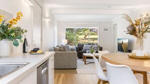 Eine moderne Küche mit Essbereich, einer Couch und Blick ins Freie.