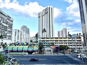 Um edifício de vários andares com um mural colorido na base, cercado por edifícios altos.
