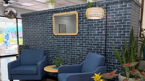 A room with two blue armchairs, a small table, and potted plants. - Central YMCA Residences (Honolulu)