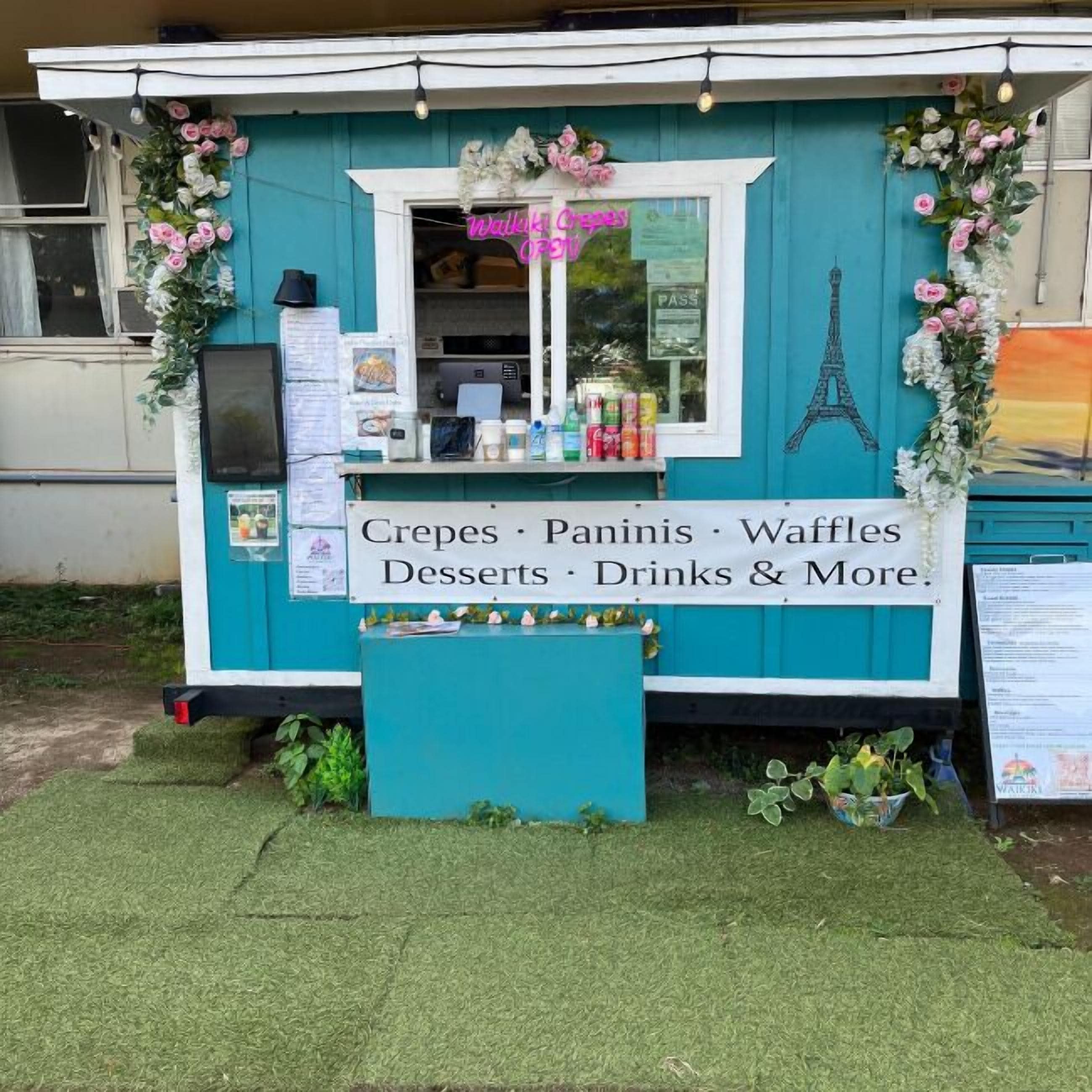 Un camión de comida con un anuncio de crepes, panini, gofres, postres, bebidas y más.