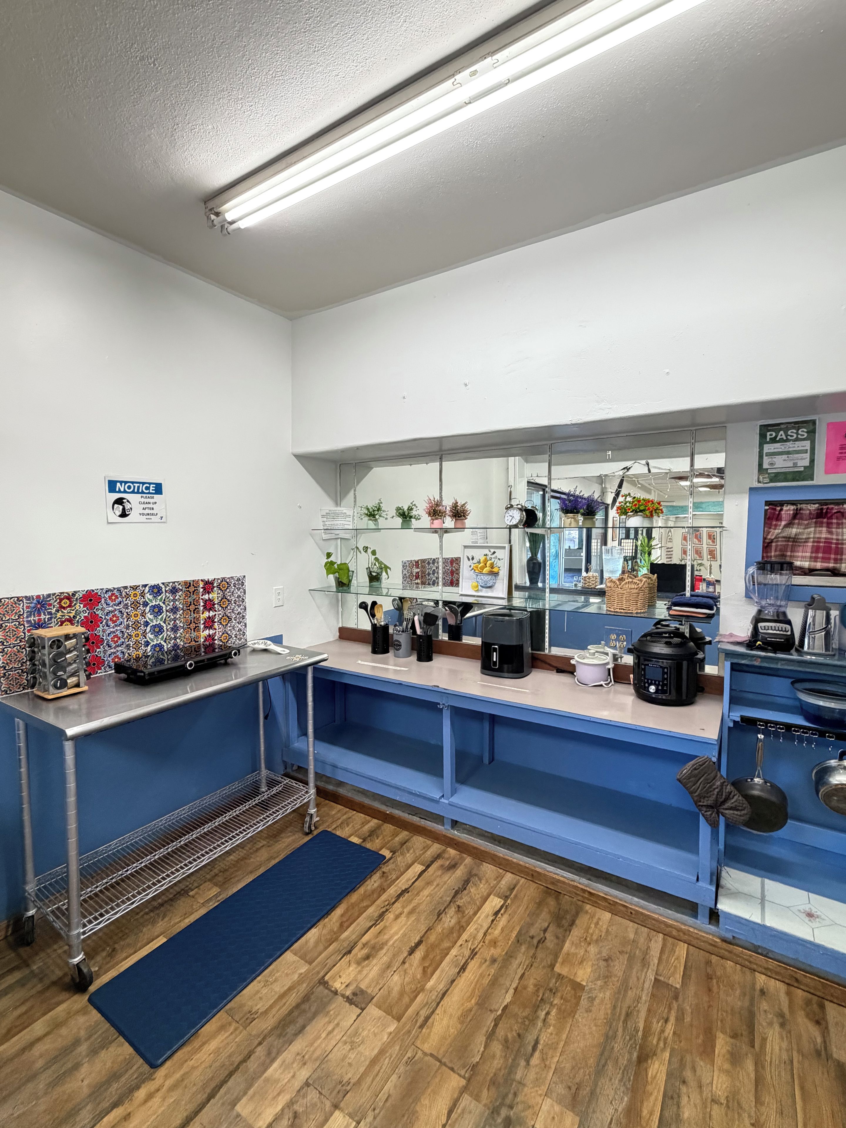 A kitchen with a blue counter, wooden flooring, and various appliances.