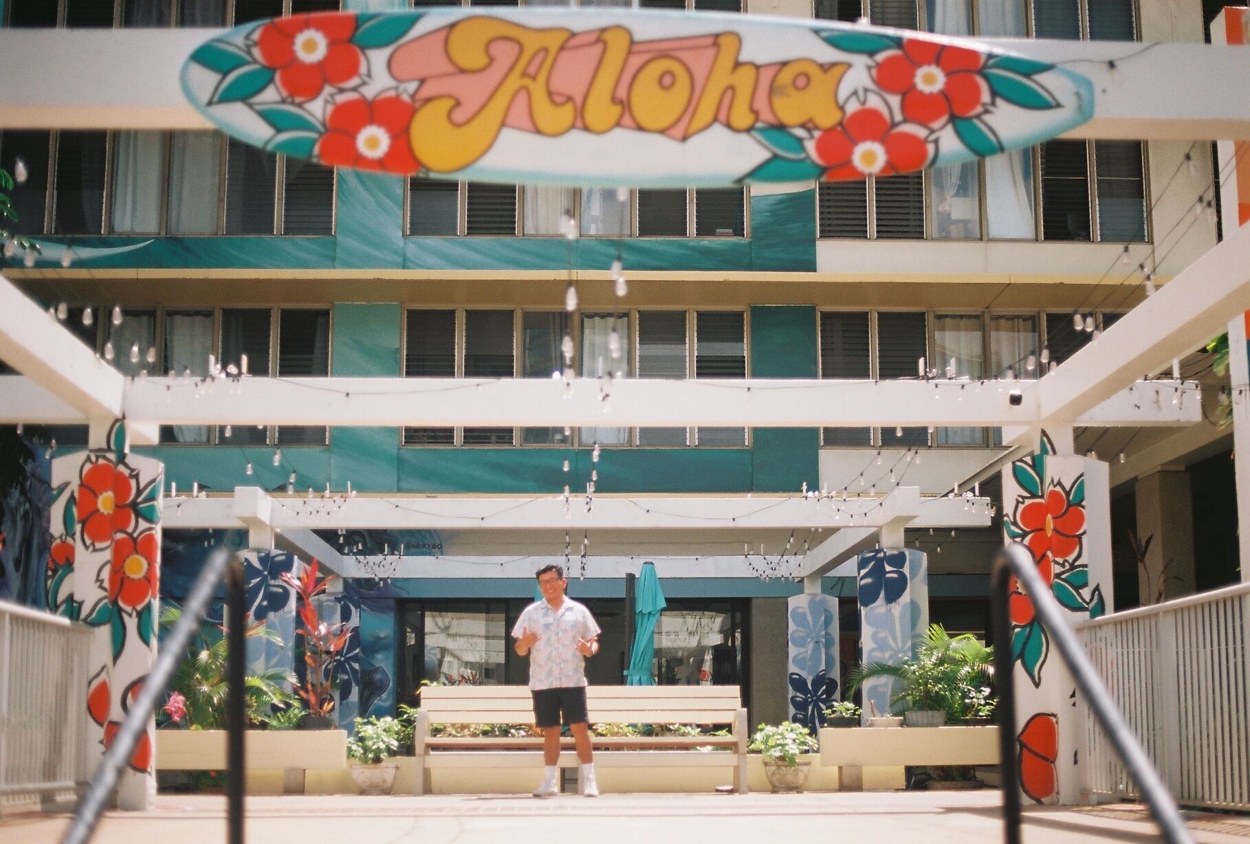 A building with a sign reading 'Aloha' and a man walking in front.