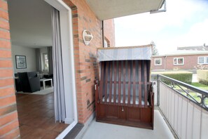 A balcony with a wooden gate, a brick wall, and a view of a residential area. - Rungholtstraße 6, Whg. 1 (Wyk auf Föhr)