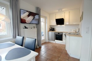 A modern kitchen with a built-in oven, a coffee maker, and a flat-screen TV mounted above the counter. - Rungholtstraße 6, Whg. 1 (Wyk auf Föhr)